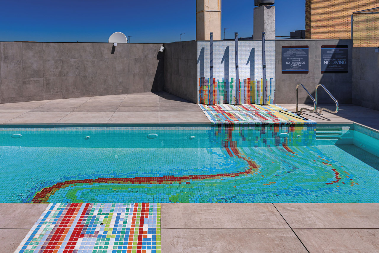 Rooftop pool with artistic mosaic tiles in vibrant colours and matching showers.