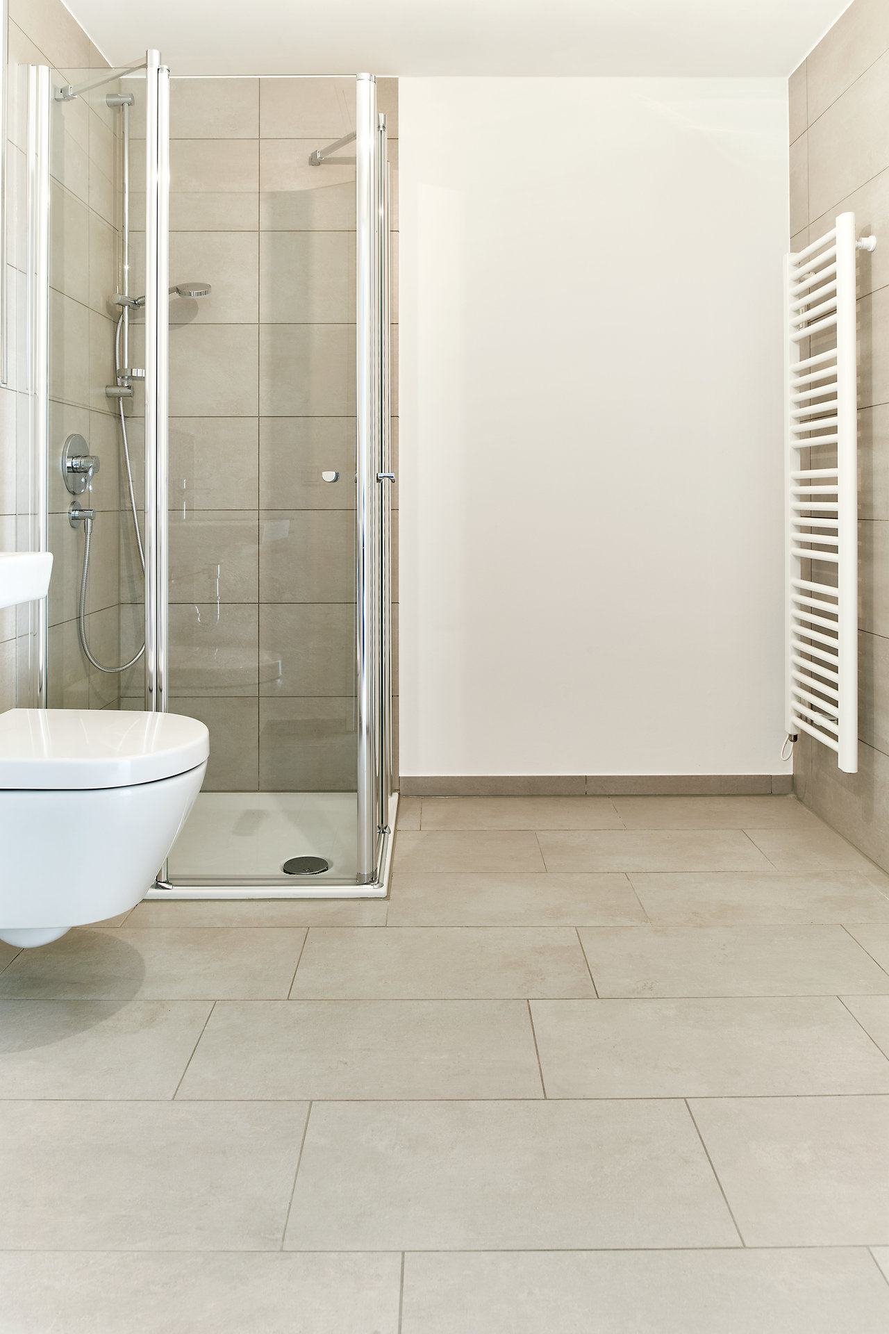 Modern bathroom with large-format light grey floor tiles and matching wall tiles.