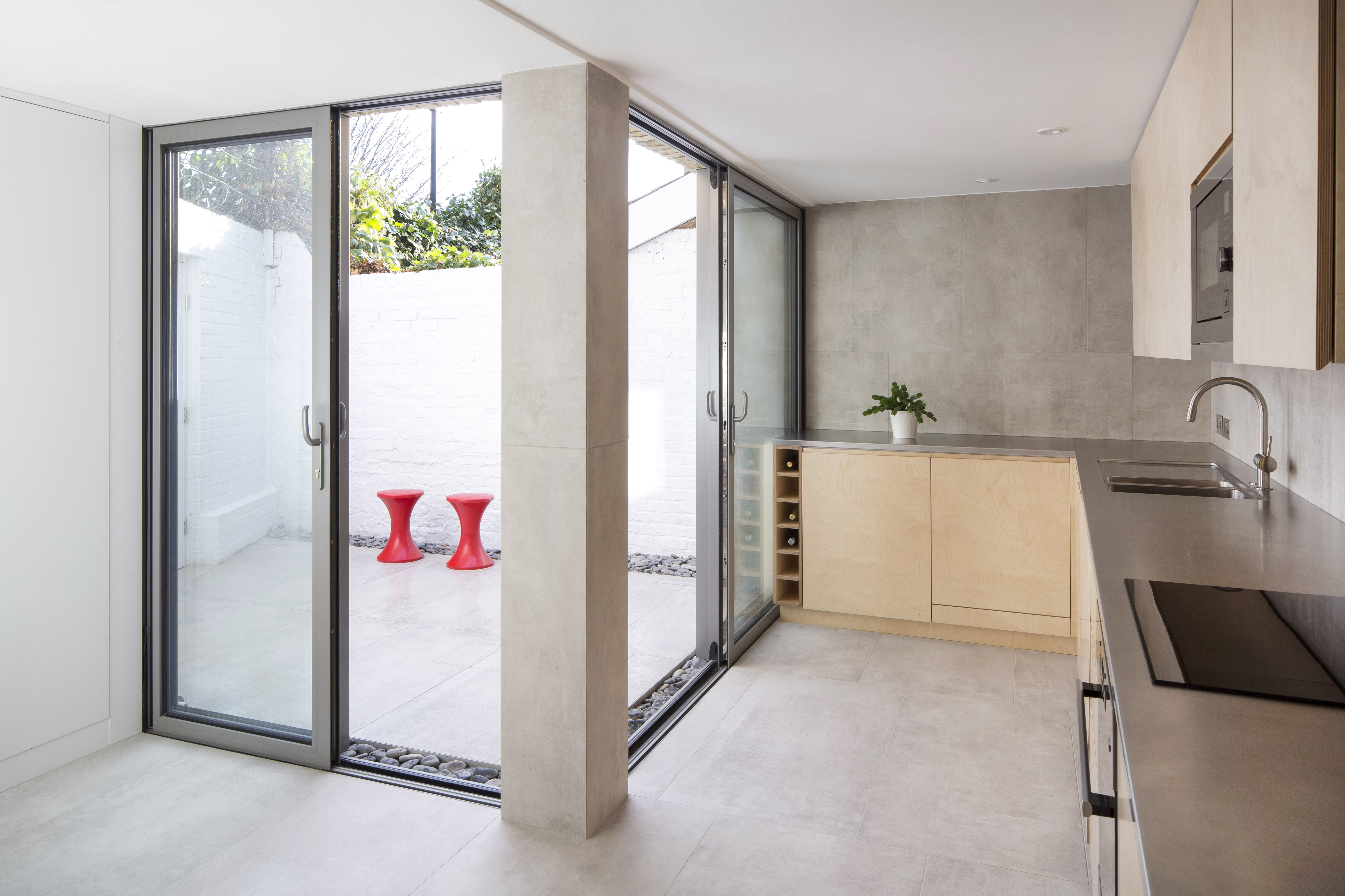 Light tiles seamlessly connect modern kitchen and outdoor terrace.