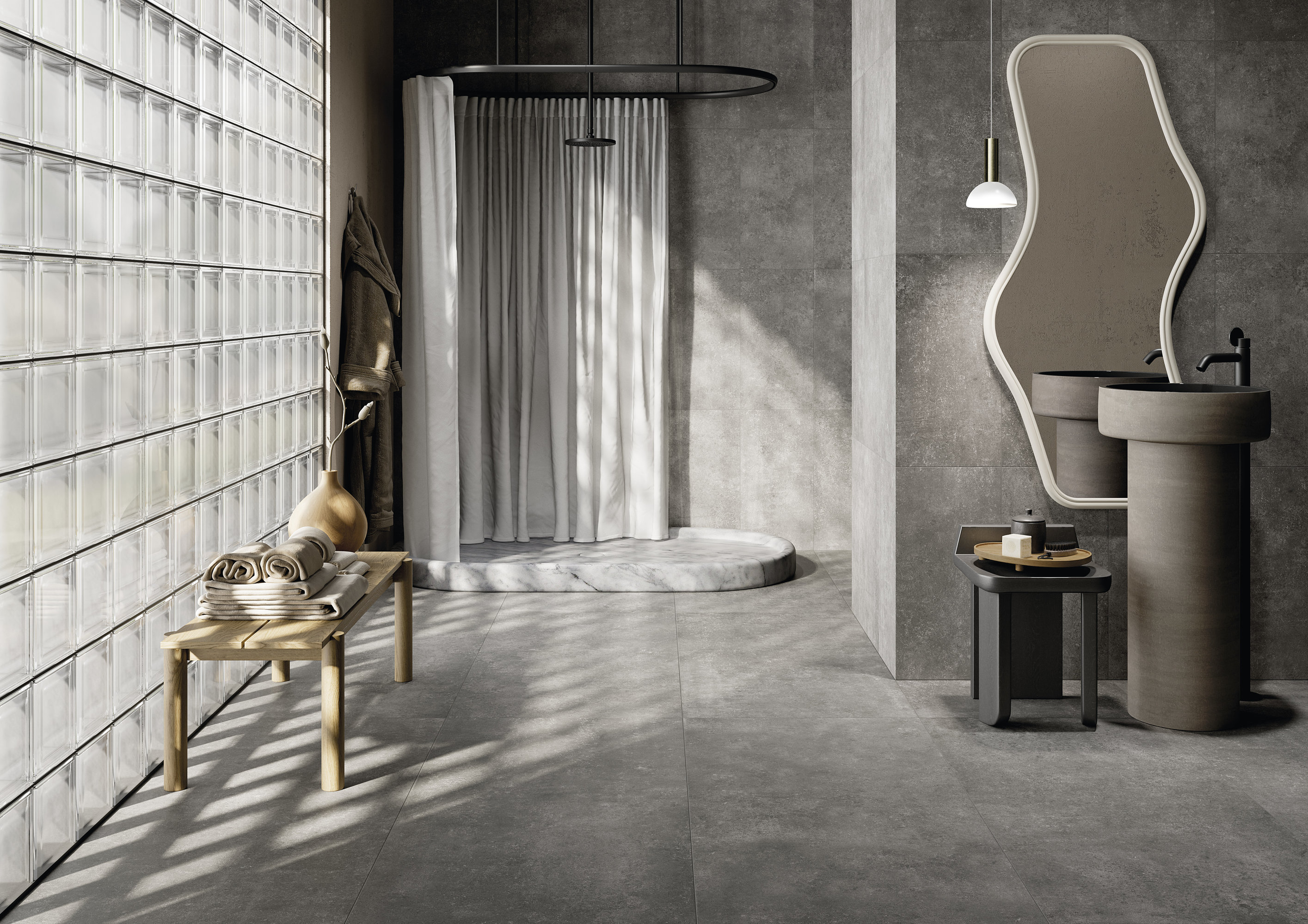 Modern bathroom with grey floor and wall tiles and a glass brick wall.