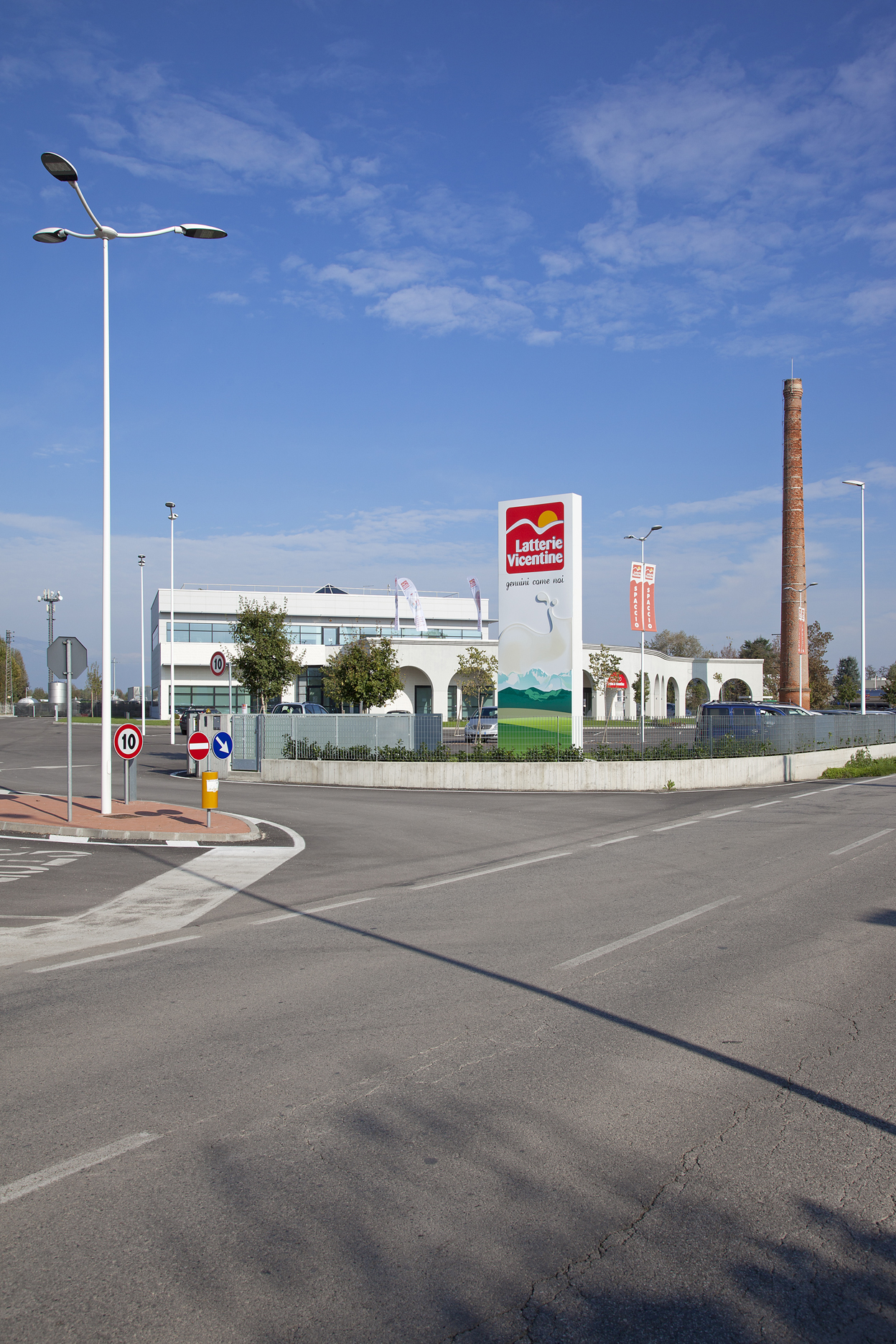 Industrial park exterior view with factory building, chimney, and company sign.