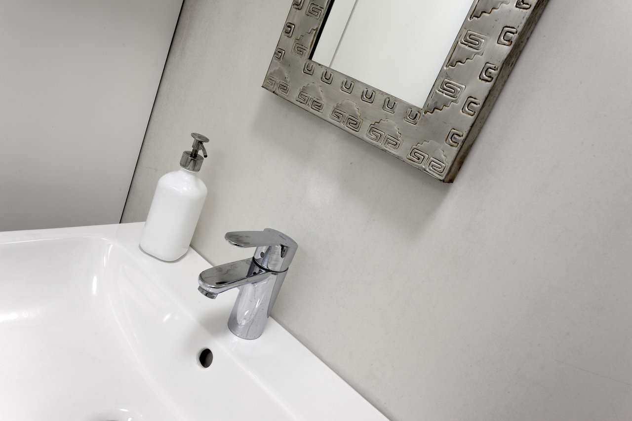 Timeless light grey bathroom tiles with white basin and mirror.