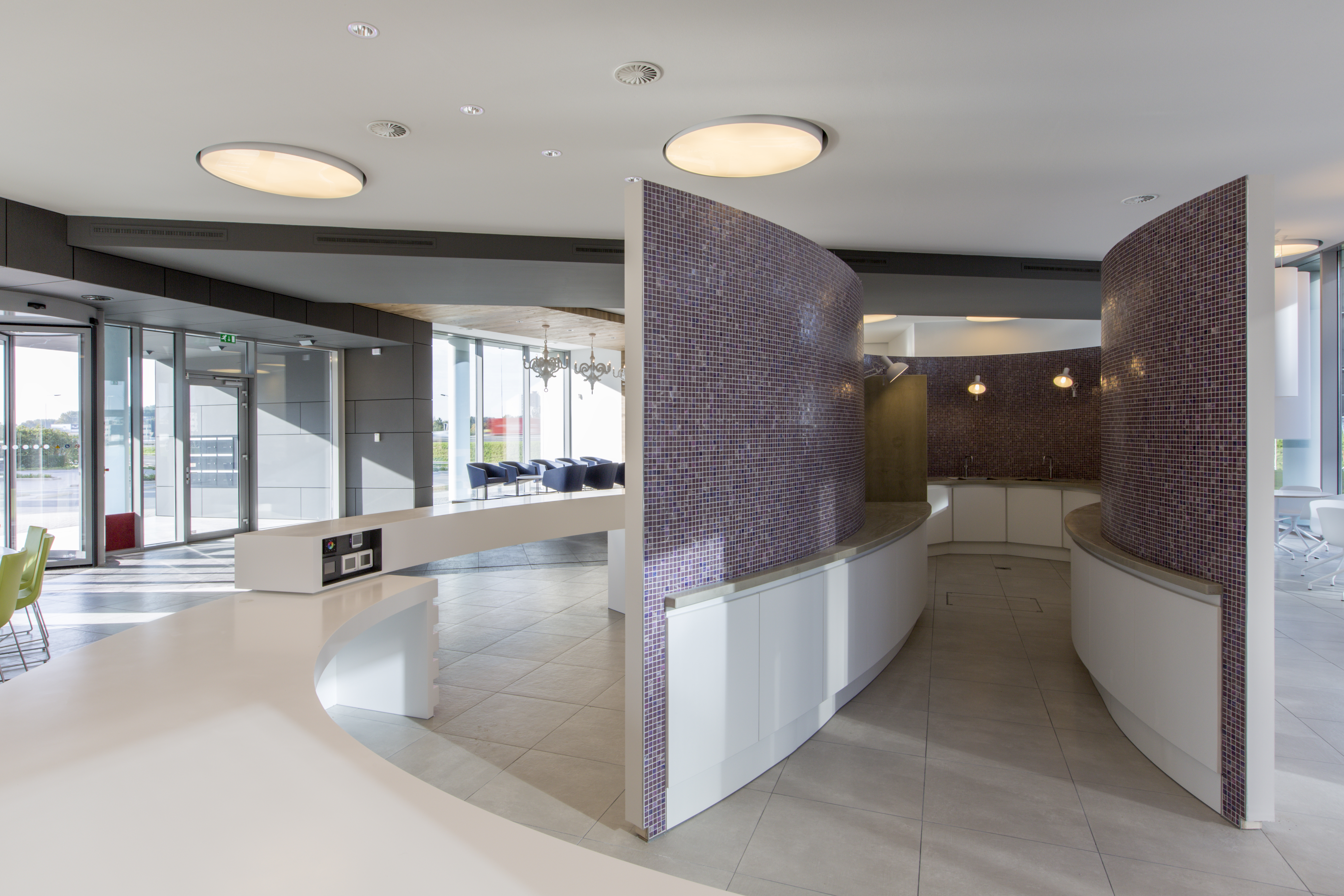 Elegant lobby with curved walls of purple mosaic tiles and a light tiled floor.