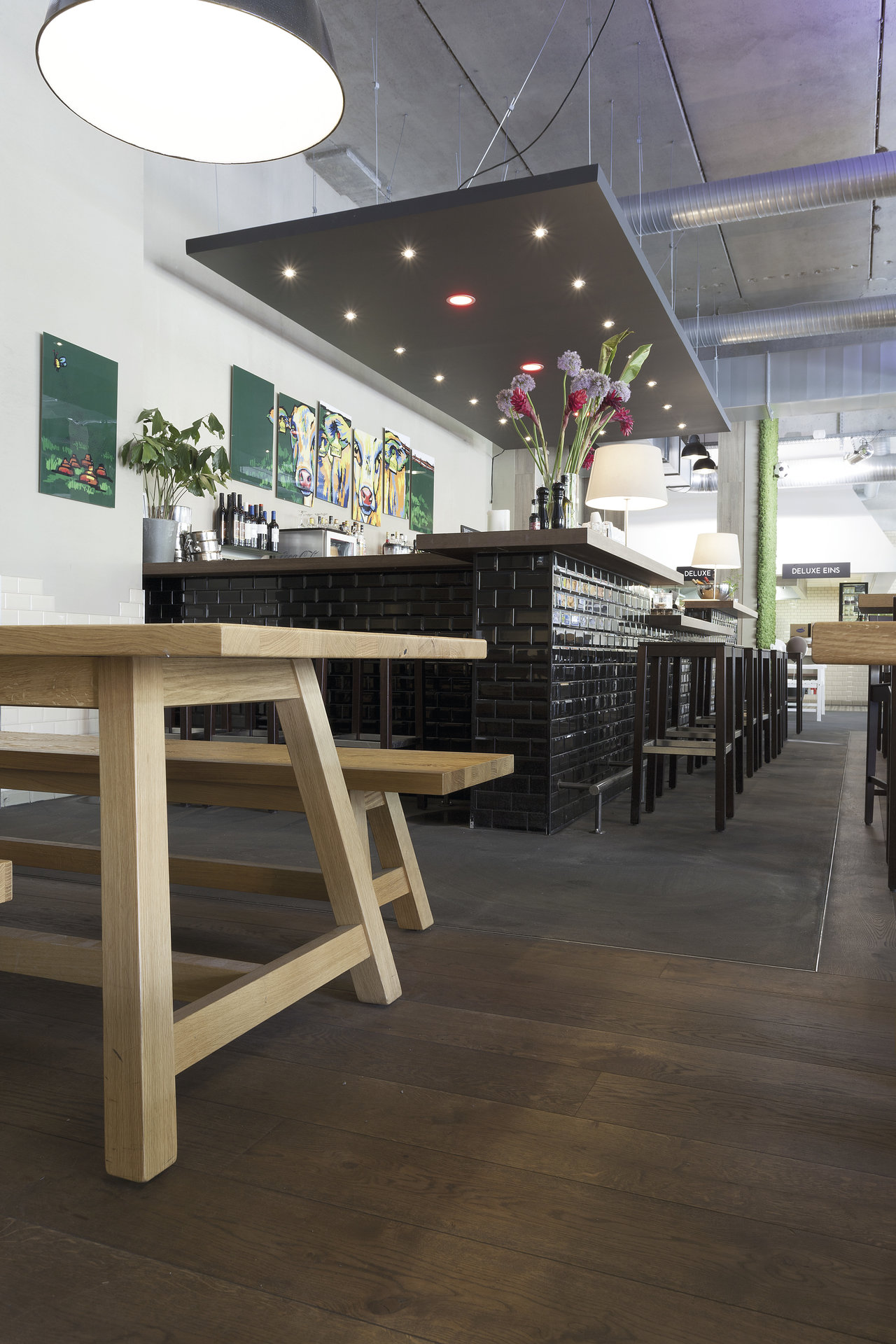 Modern catering area with dark wood-look tiles and a bar with black subway tiles.