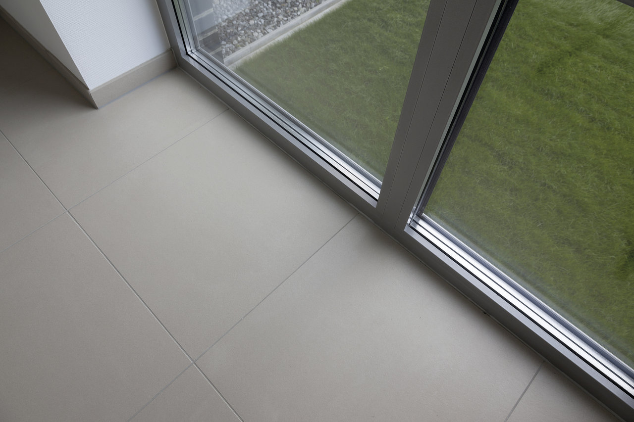 Light, large-format indoor tiles overlooking a green outdoor space.