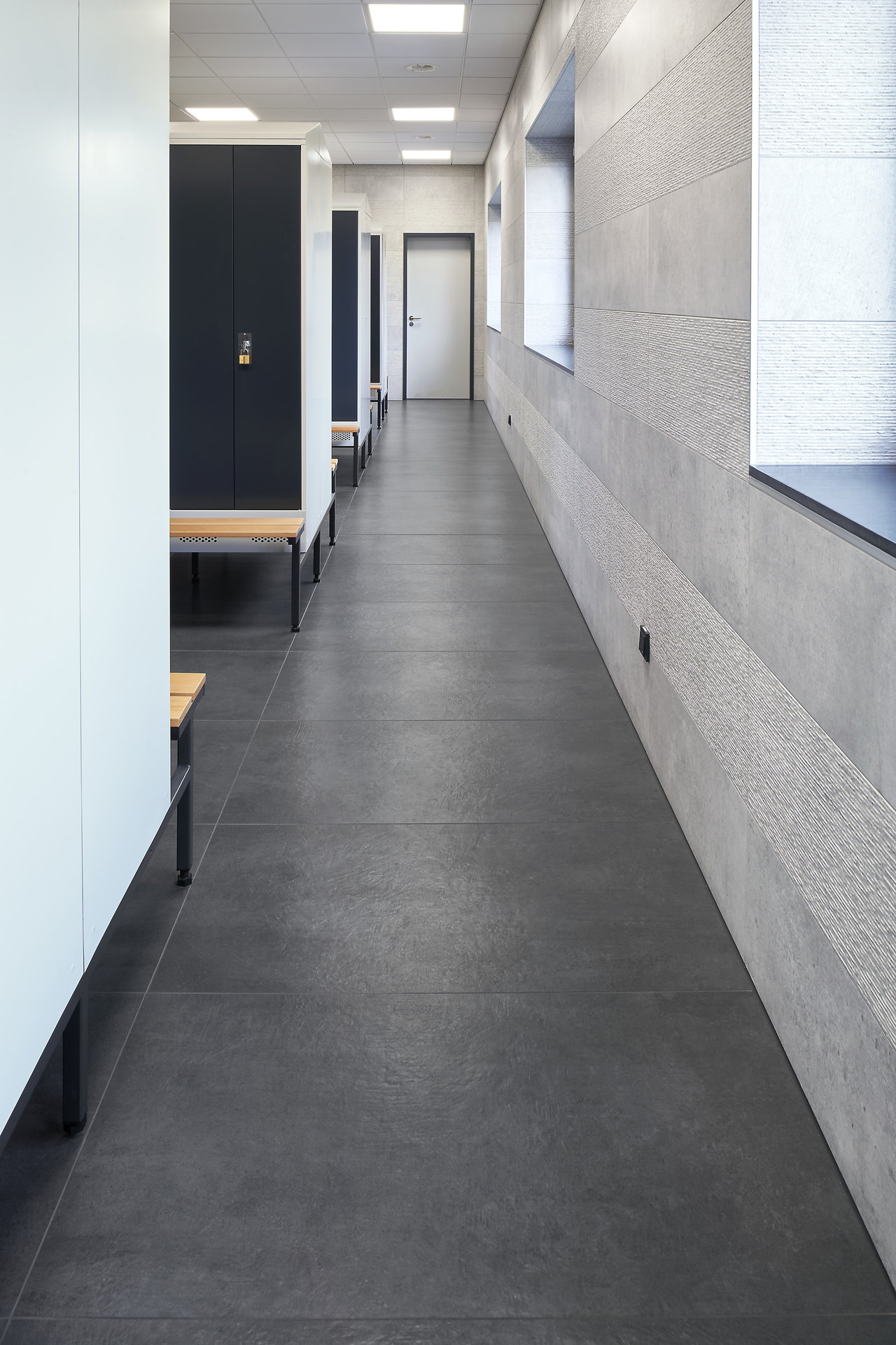 Modern changing area with anthracite floor tiles and light grey wall tiles.
