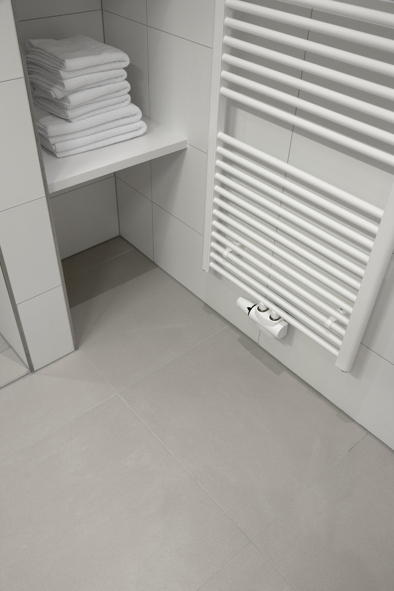 High-quality light grey floor tiles and white wall tiles in a modern bathroom.
