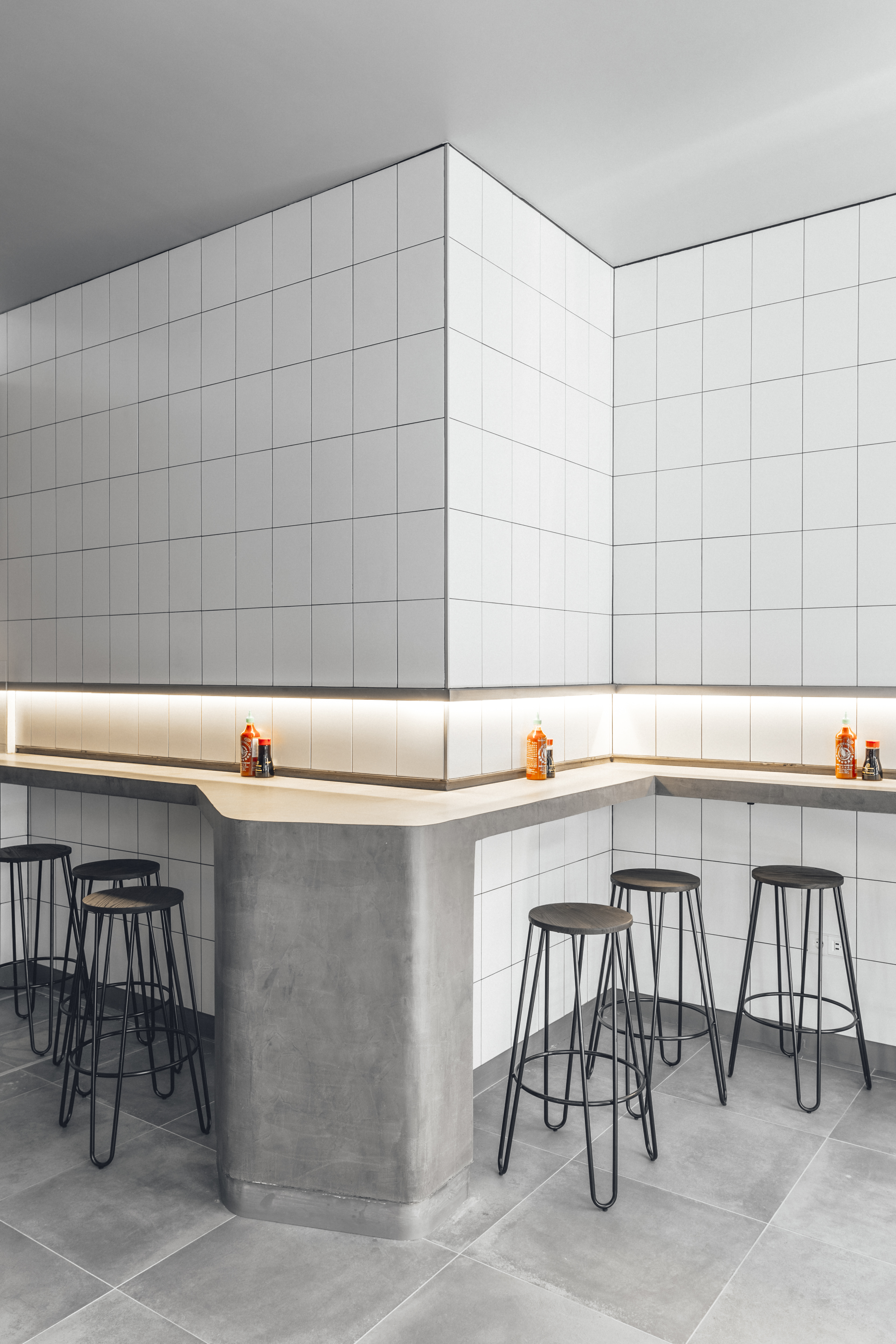 Bright white wall tiles and large-format grey floor tiles in a modern interior.