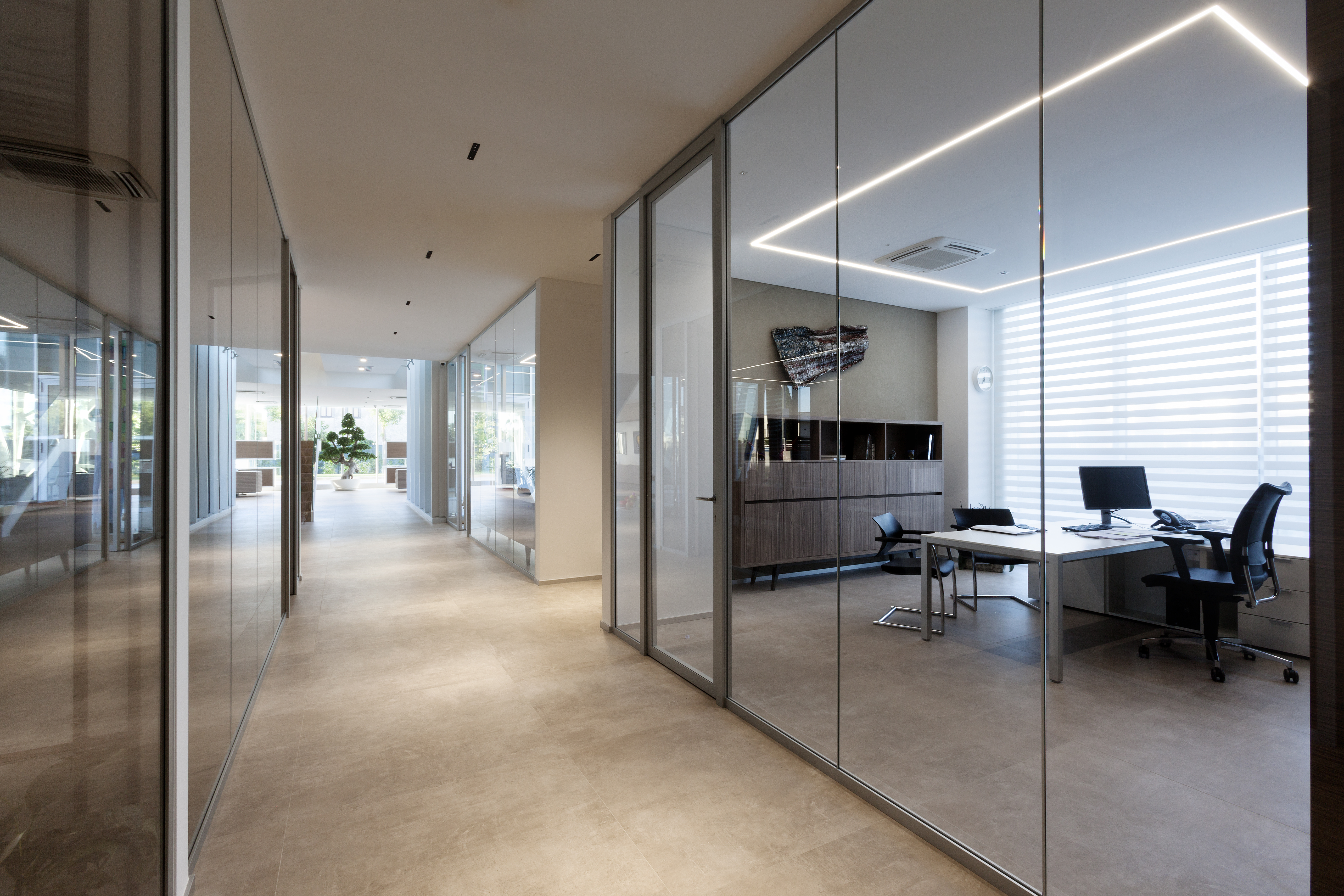 Bright, large-format tiles in a modern office hallway with glass walls.