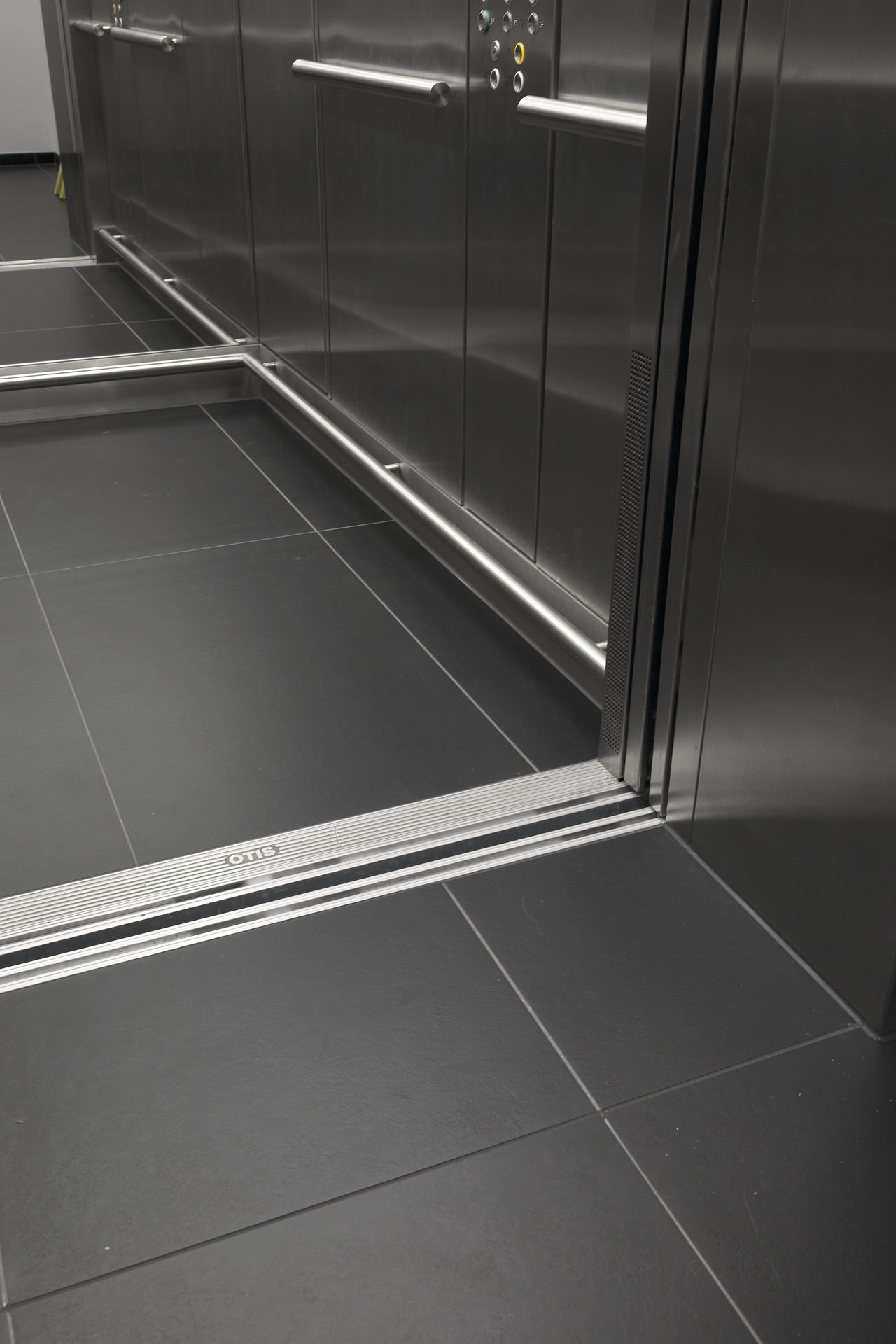 Dark, large-format tiles in a modern elevator area.