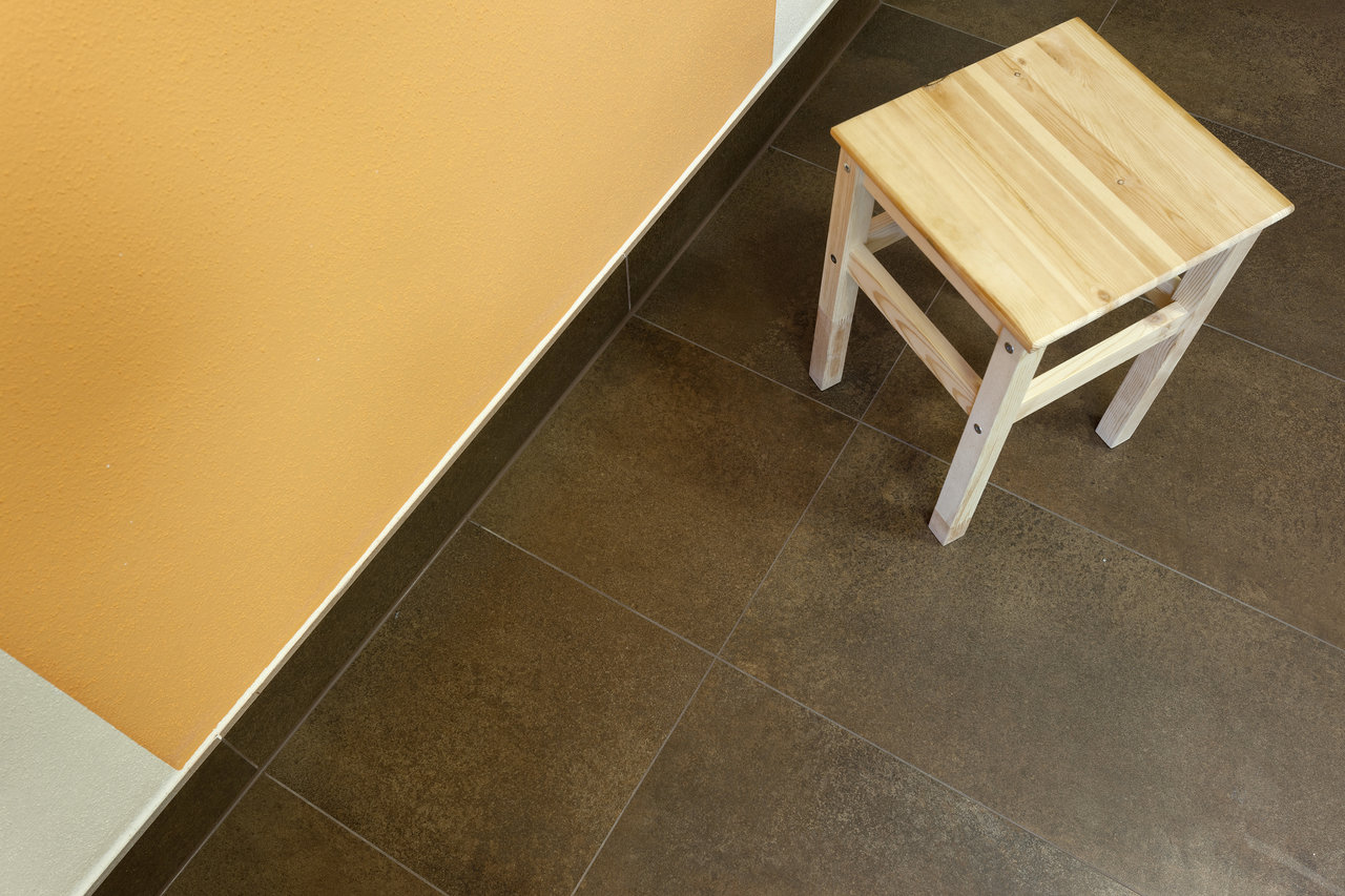 High-quality dark brown floor tiles with a matte surface and a wooden stool.