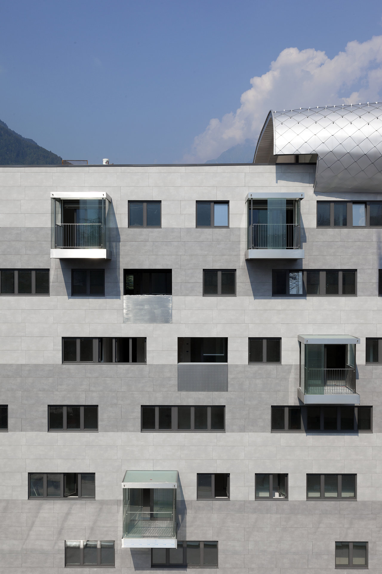 Modern grey tile facade with windows and balconies.