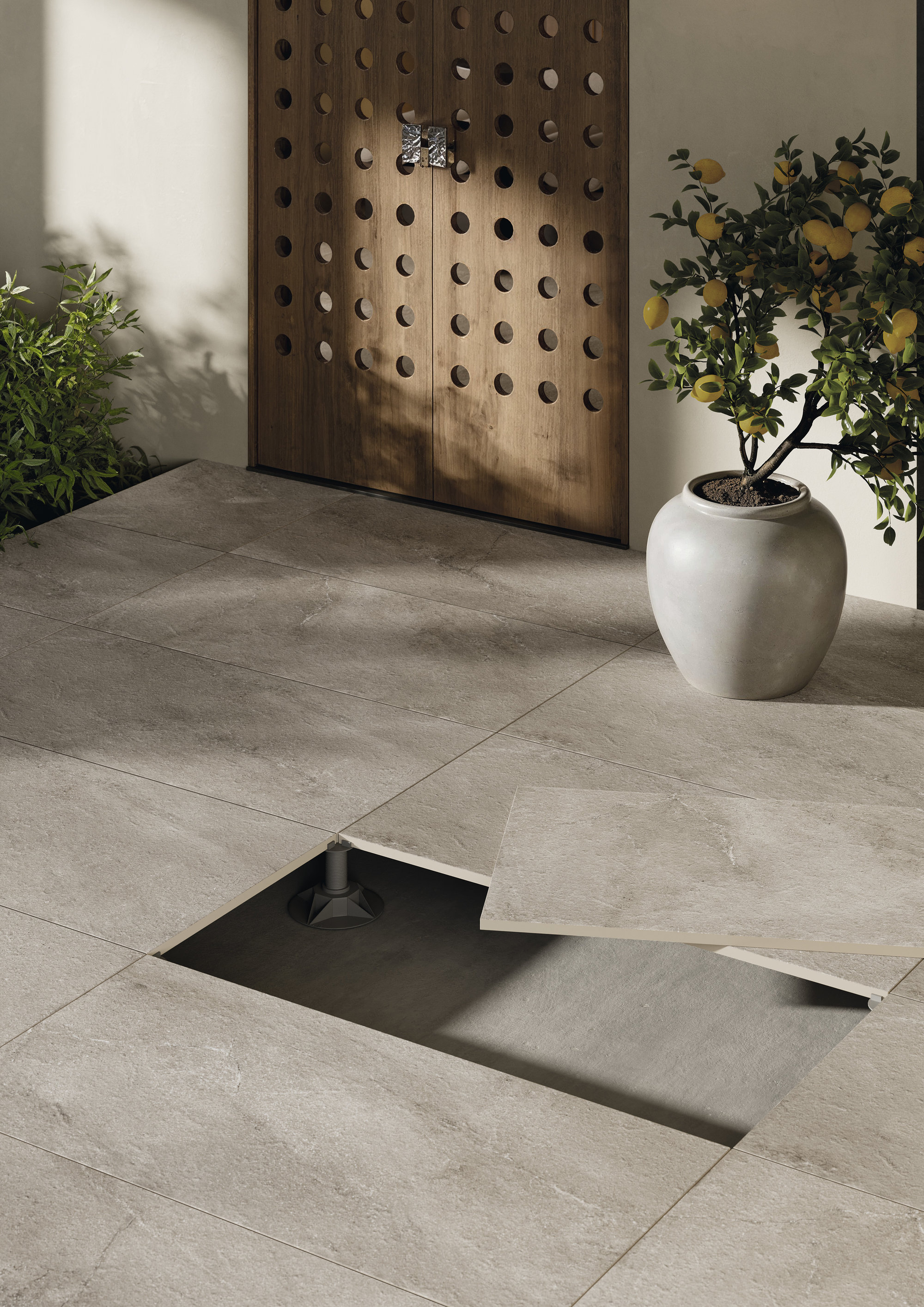 Grey outdoor tiles on pedestals, one lifted to reveal the drainage system.