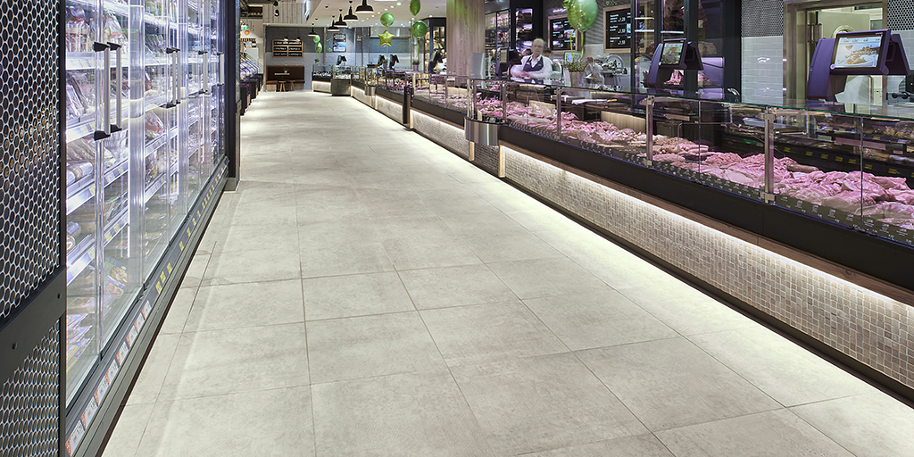 Large-format, light grey floor tiles in a modern grocery store.