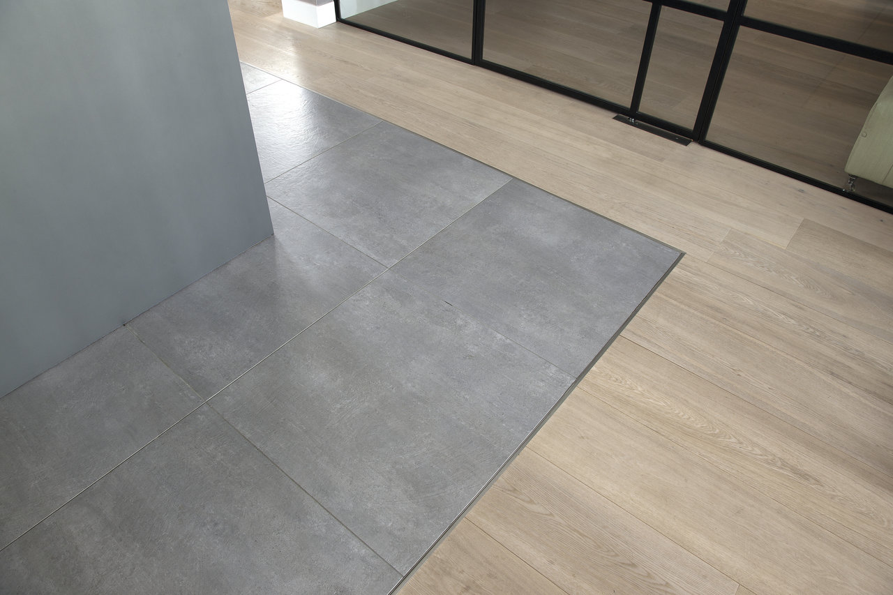Modern grey tiles and light wood-effect flooring in a stylish transition.