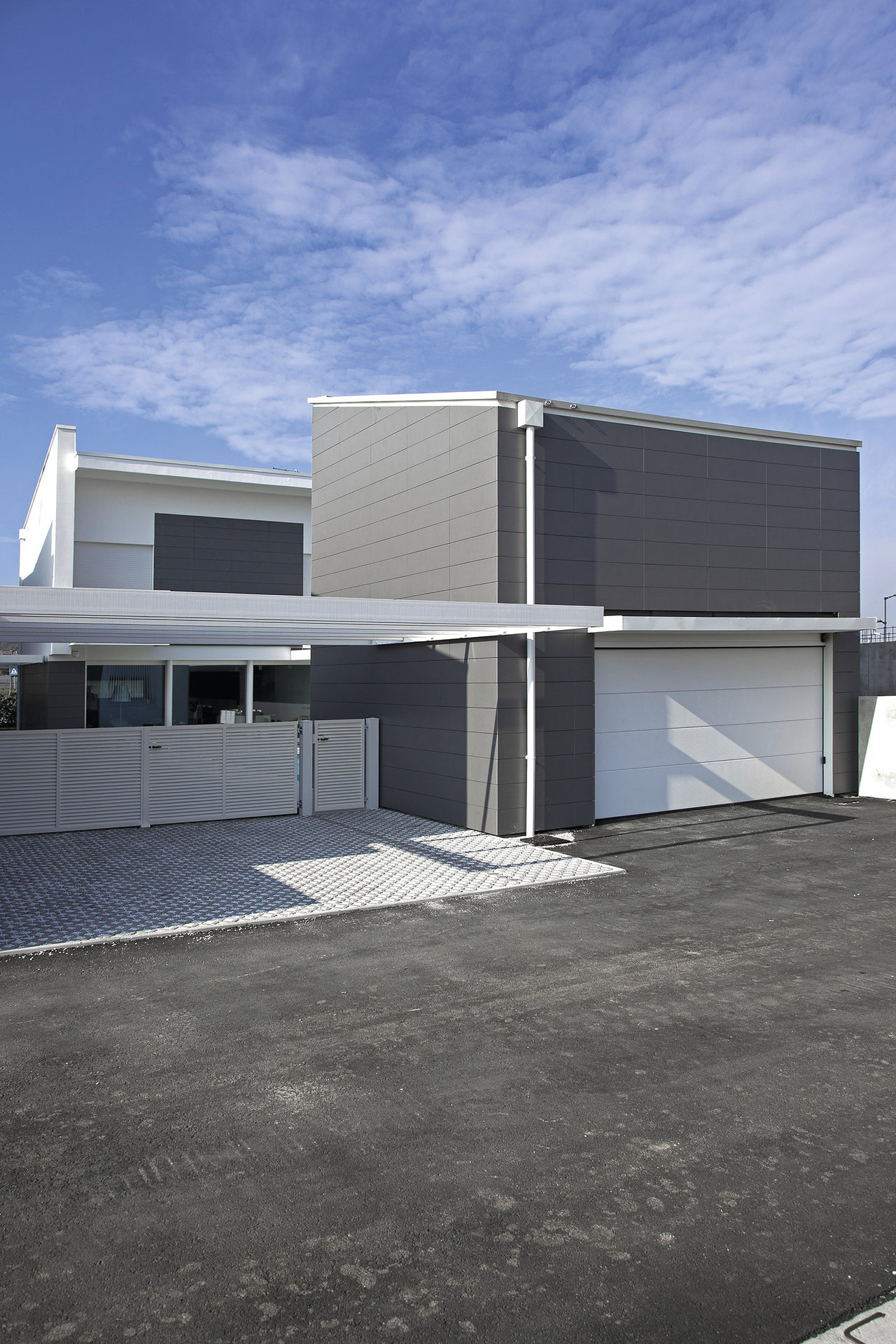 Modern house with grey facade tiles and light outdoor paving.
