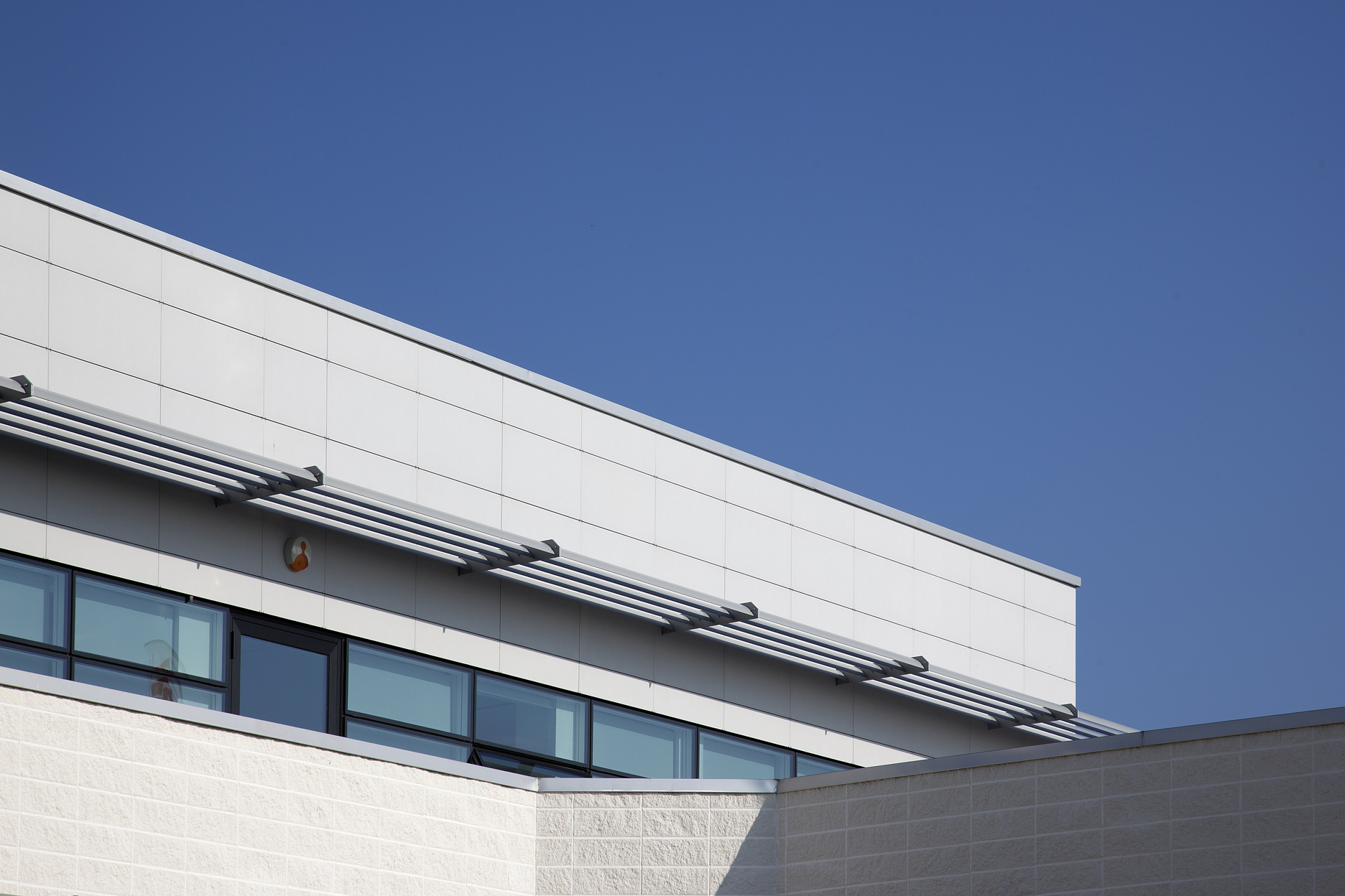 Modern bright facade with large tiles under a blue sky.