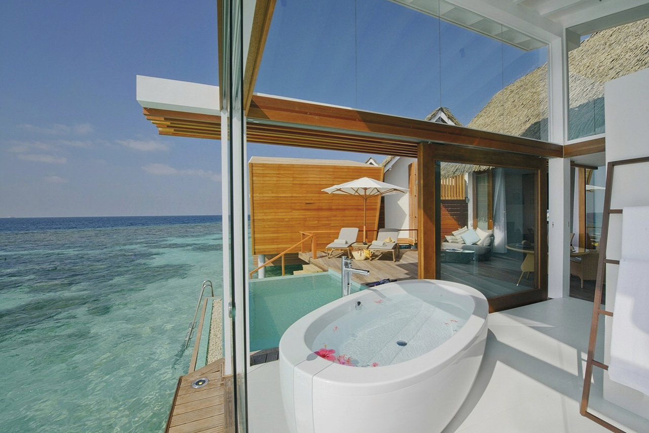 Bright bathroom with freestanding tub, sea view & elegant tiled floor.