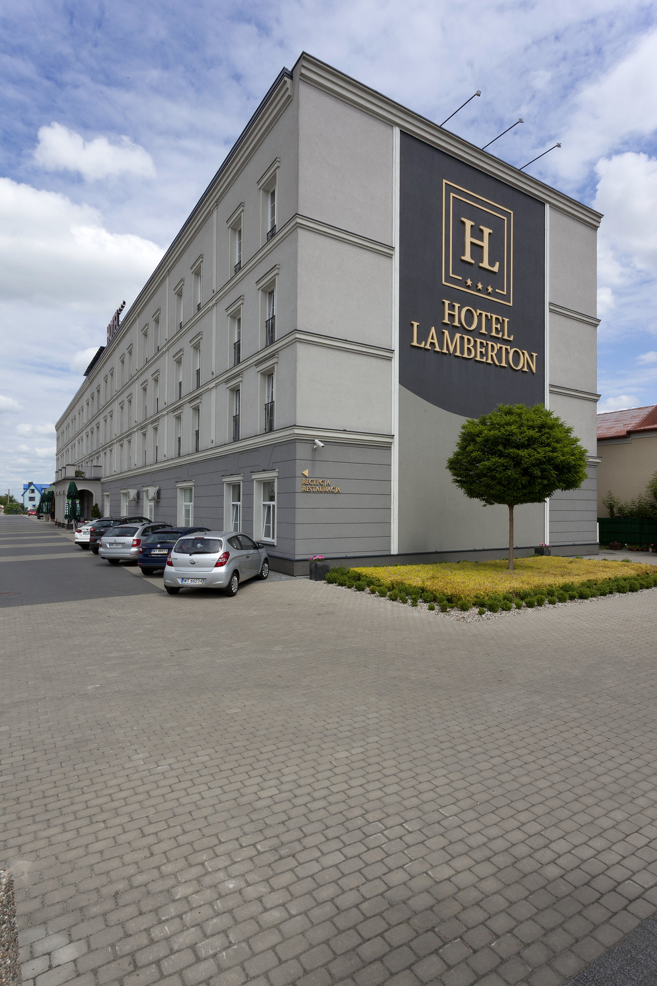 Grey outdoor tiles in modern hotel entrance with parking.