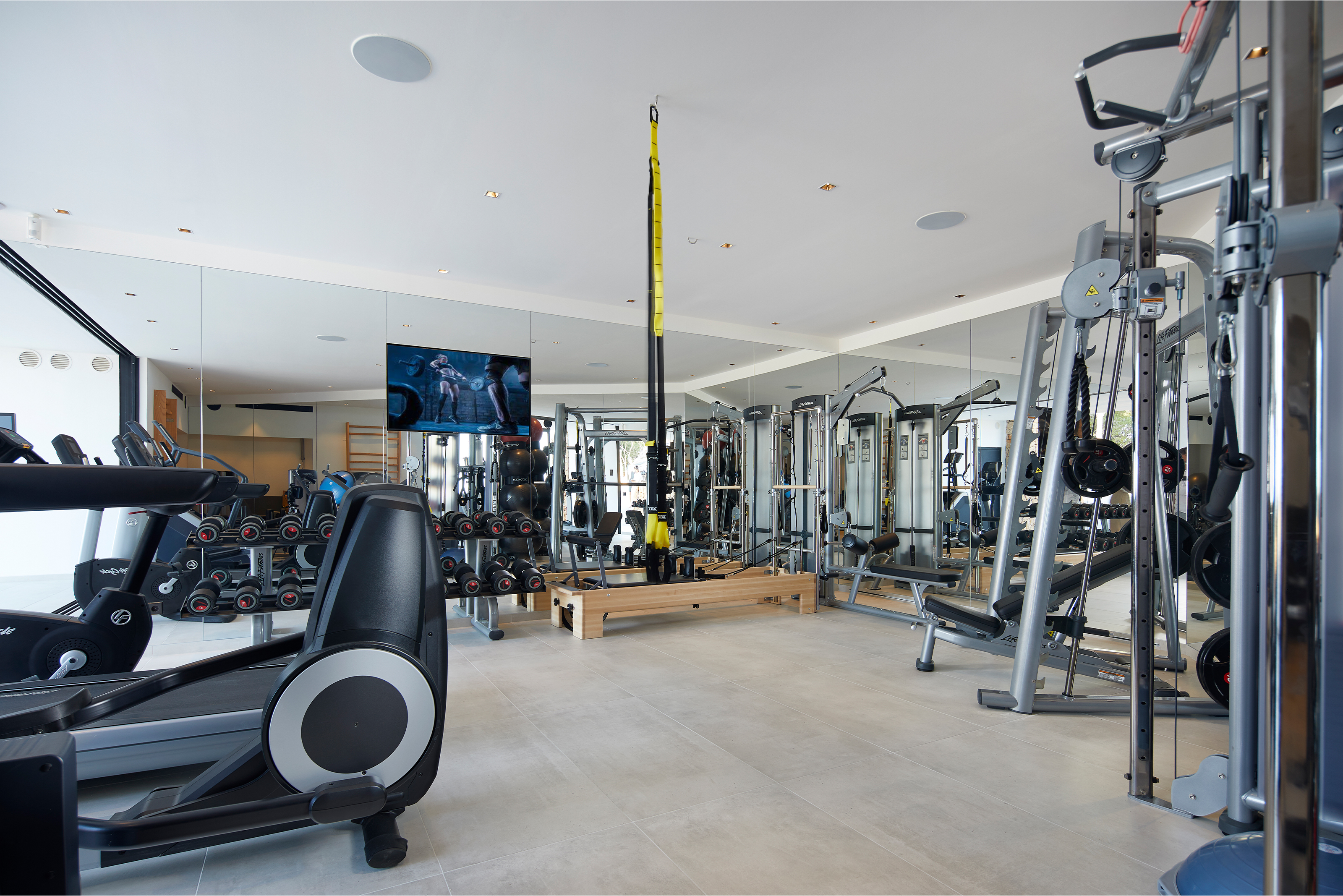 Spacious fitness area with elegant floor tiles and gym equipment.