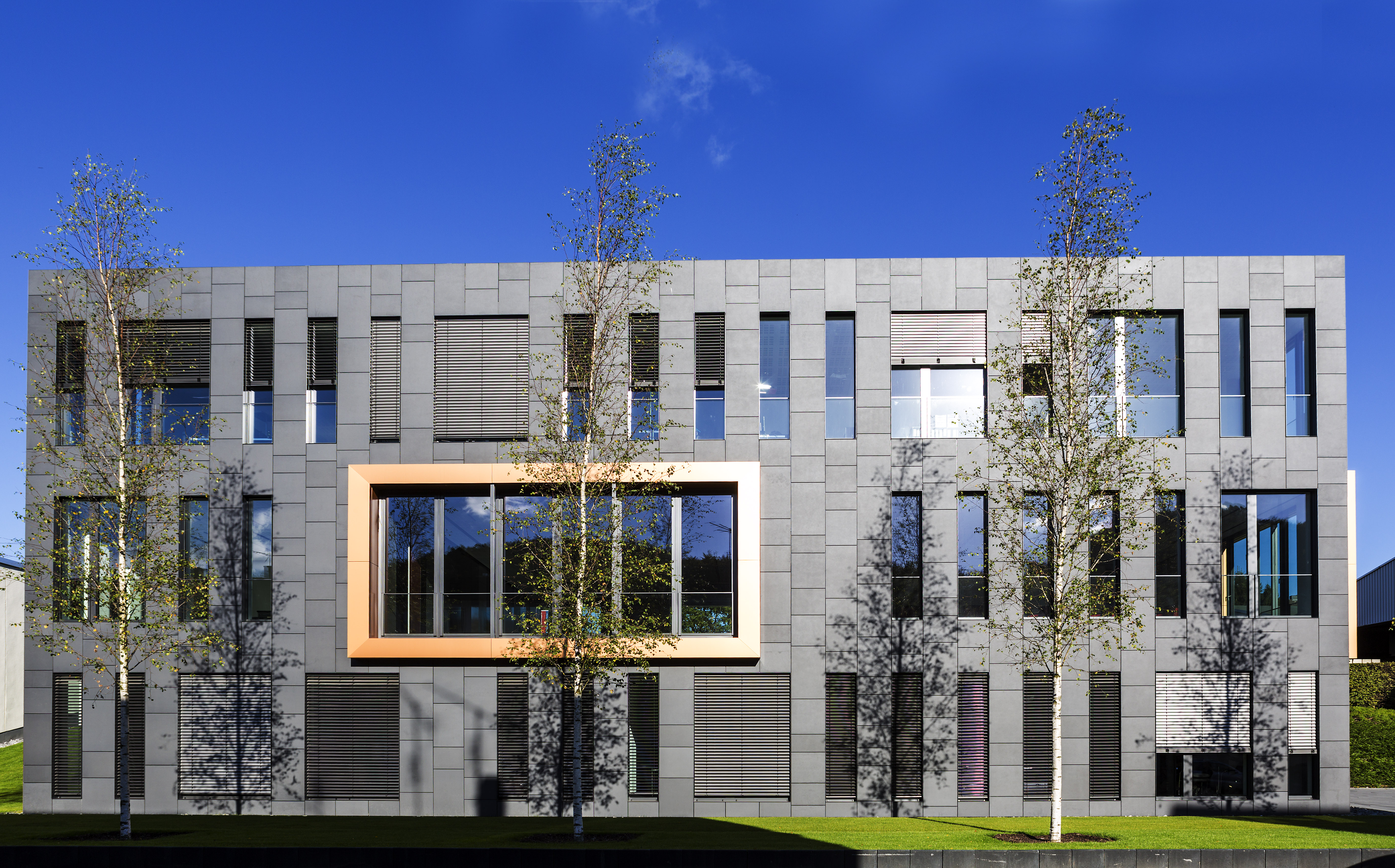 Modern architecture with grey tile facade and golden accent window, suitable for Porcelaingres.
