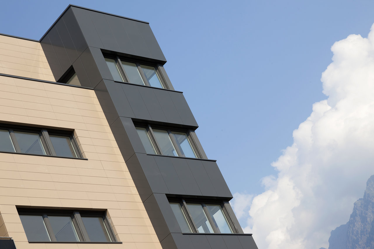 Modern building facade with beige and anthracite tiles.