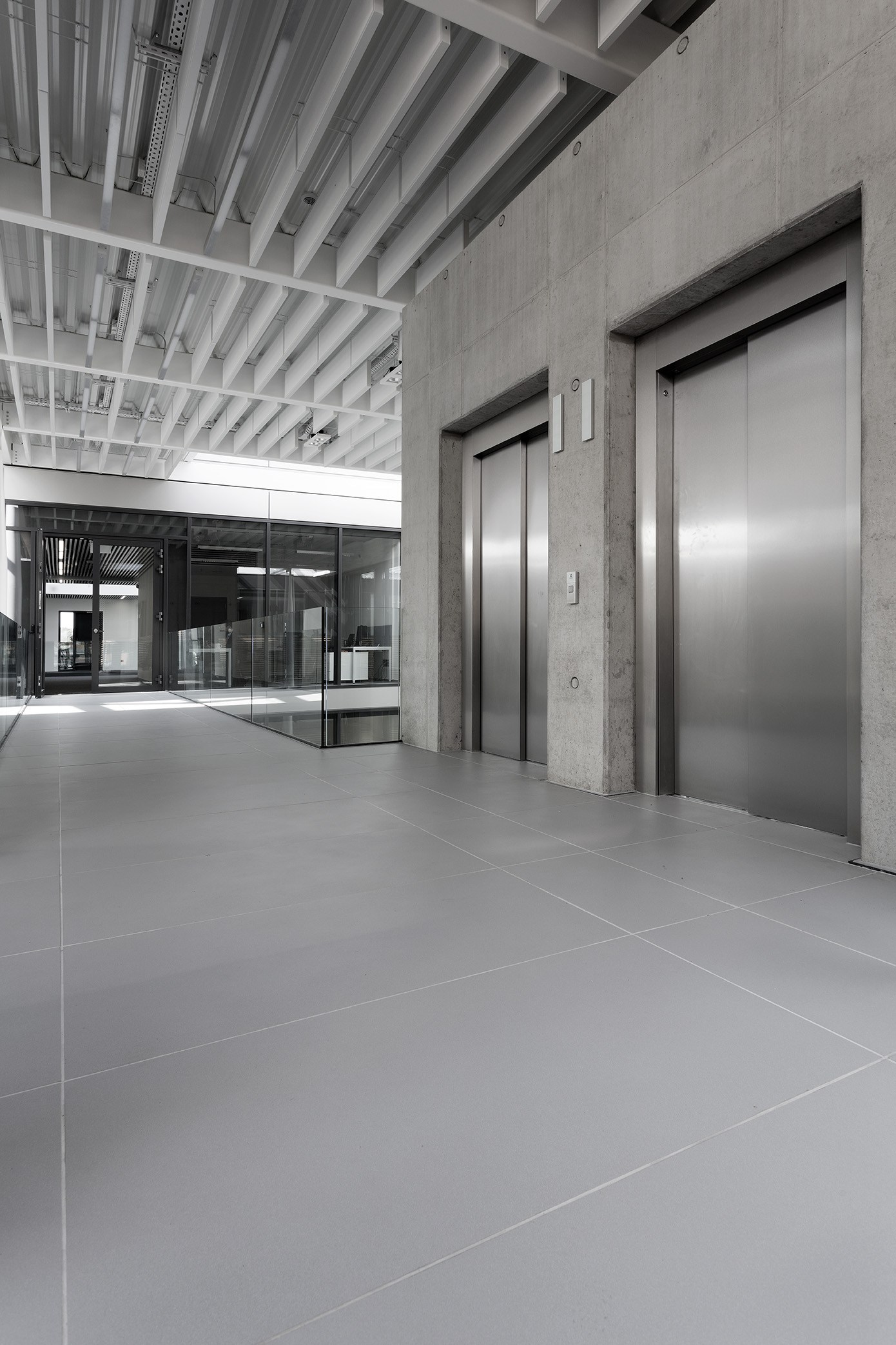 Grey, large-format tiles in a modern entrance with lifts.